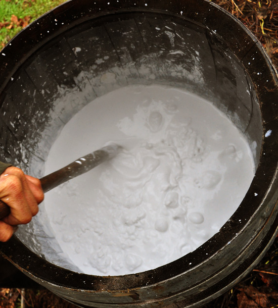 Slaking quicklime in a barrel.  Note the bubbles, this is actually boiling from the violent reaction when water is made available.